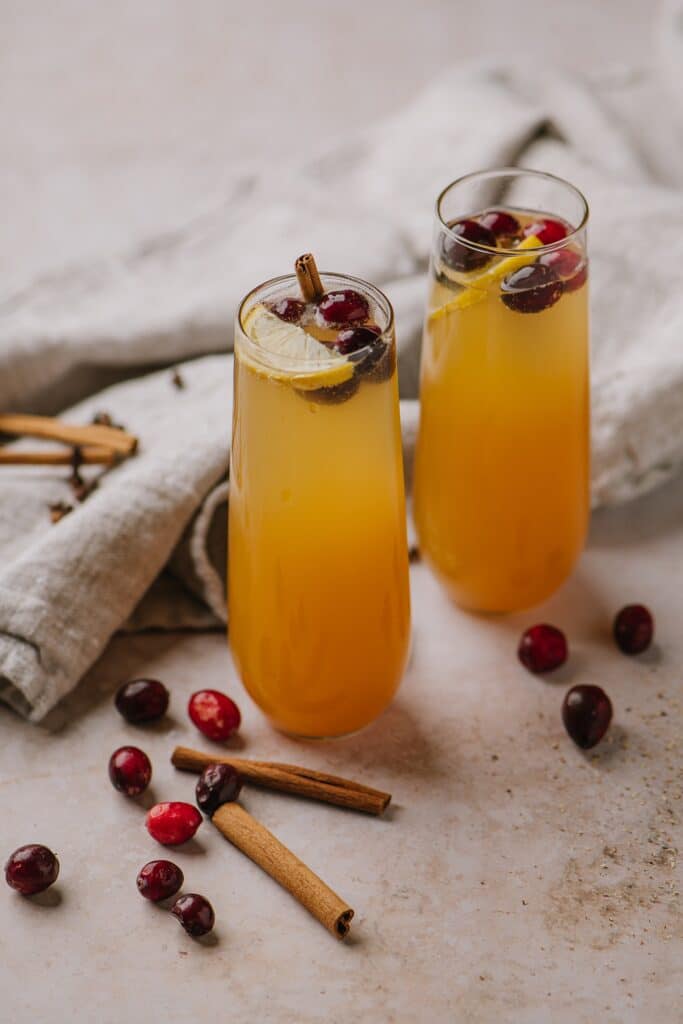 Spiced Apple Cider cocktails in another form, with champagne, topped with cranberries and orange